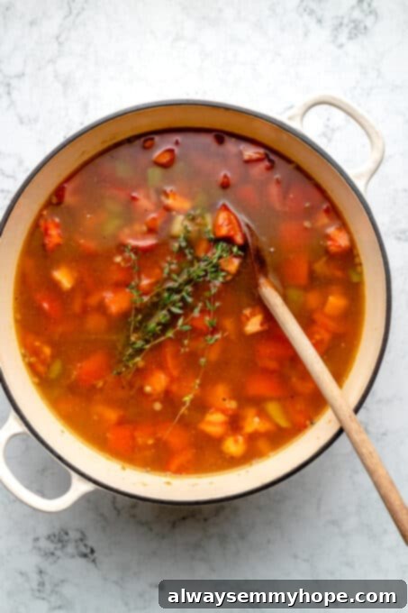 Overhead view of thyme sprigs set on top of lentil soup in pot