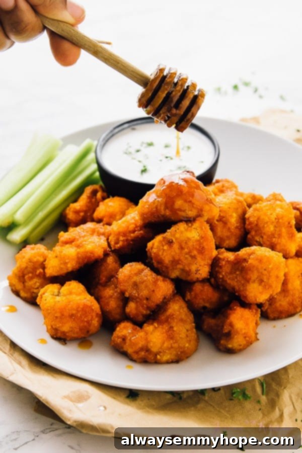 A batch of vegan cauliflower buffalo wings being drizzled with honey.