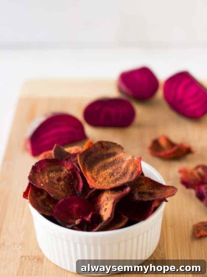 A ramekin of beet chips on a wooden board.