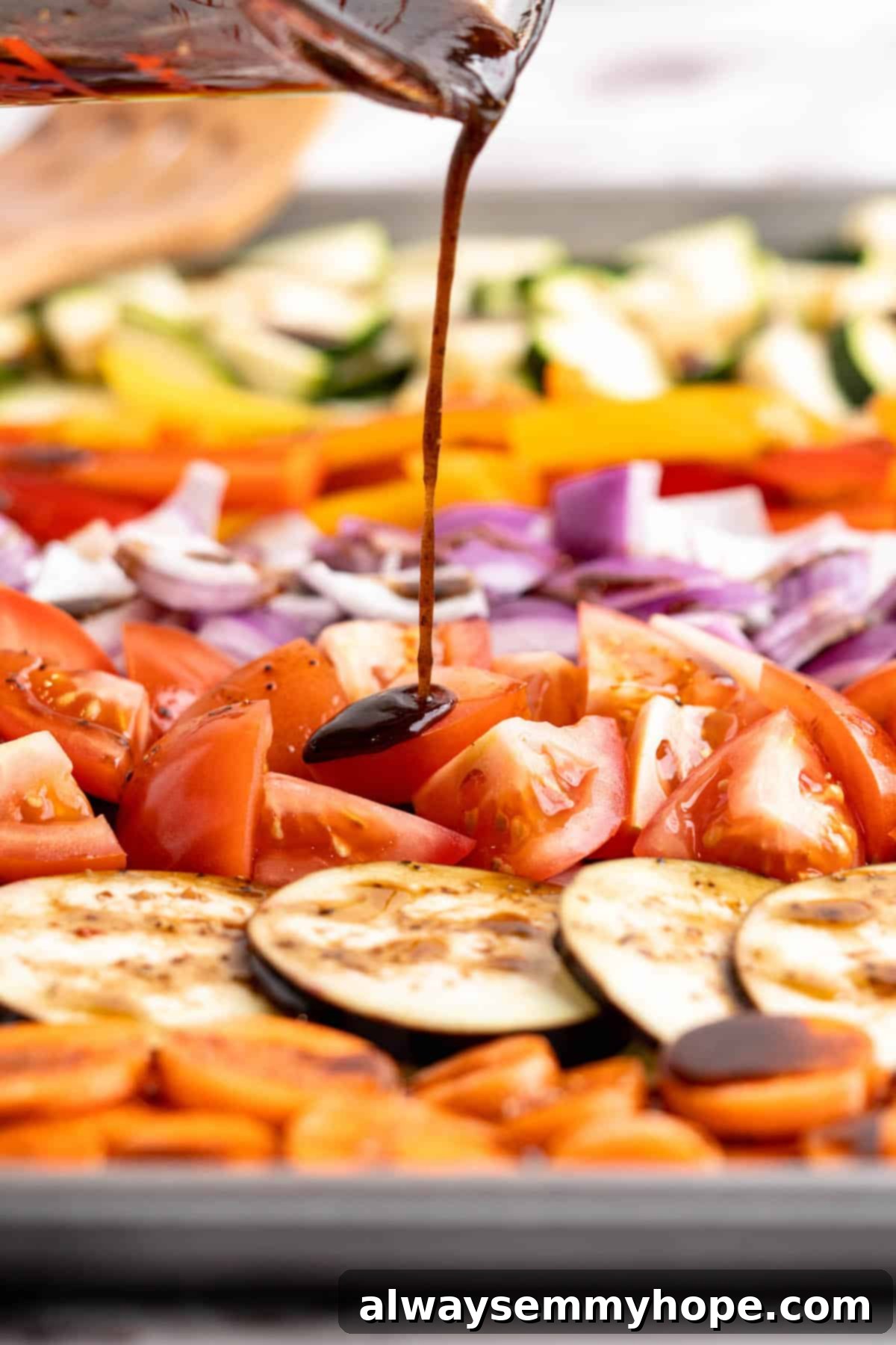 Easy Balsamic Roasted Vegetables 7 A skilled hand pouring rich balsamic marinade over a colorful mix of raw vegetables meticulously arranged on a baking sheet, ready for roasting.