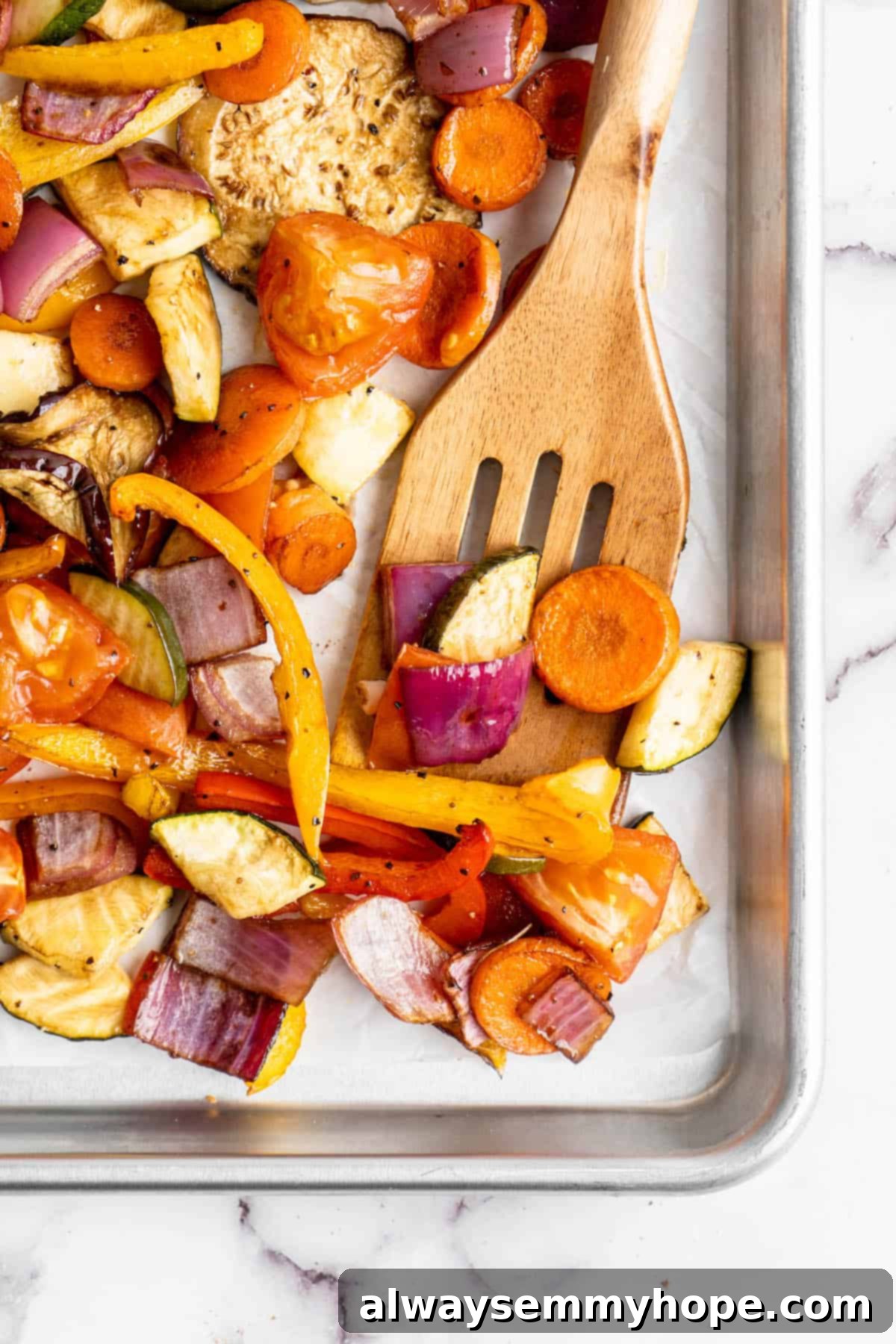 Easy Balsamic Roasted Vegetables 8 A wooden spoon carefully lifting perfectly roasted balsamic vegetables from a sheet pan, showcasing their golden-brown edges and tender texture.