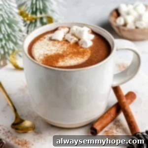 Mug of vegan hot chocolate on a round marble slab with a spoon and cinnamon sticks.