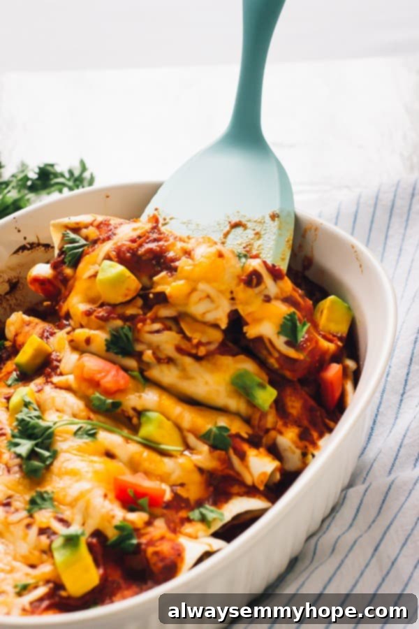 Black bean enchiladas in a baking dish with a spatula. 