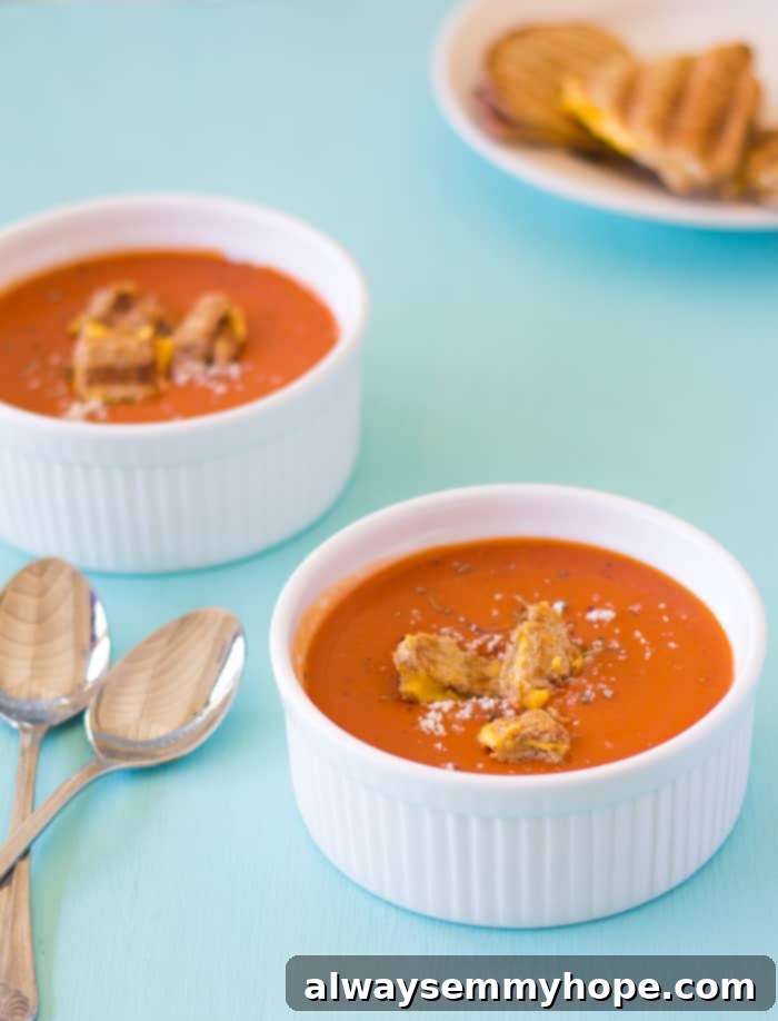 Roasted tomato soup in two ramekins with spoons on the side. 