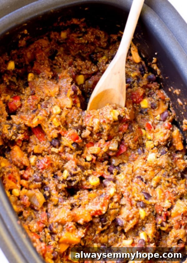 Top down shot of quinoa chili being stirred in a black pot. 
