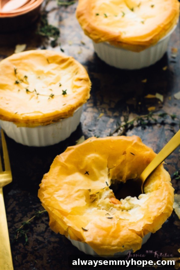 Three vegan pot pies in ramekins with a gold spoon in one. 