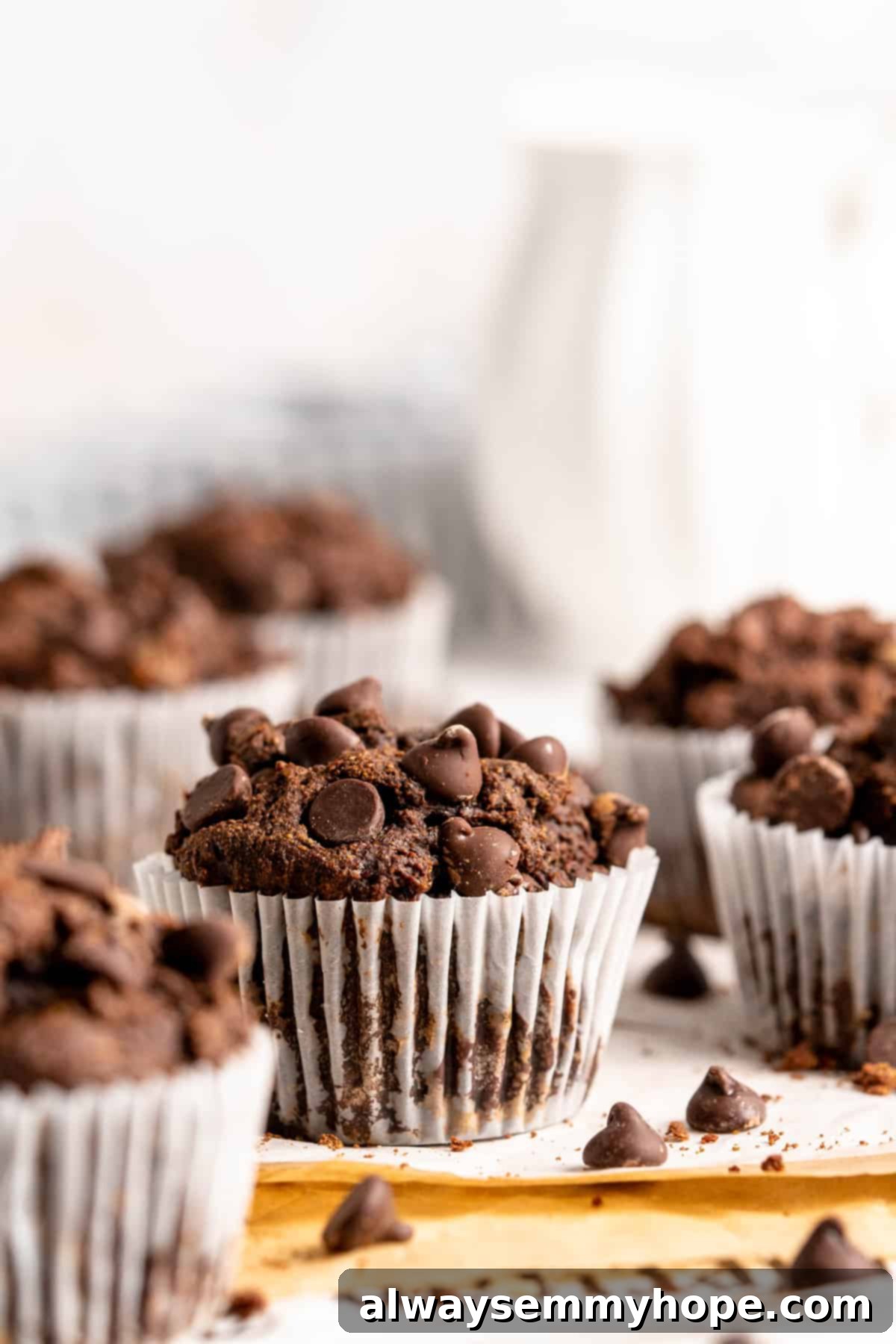 These easy chocolate banana muffins are moist, soft, and bursting with chocolate. They're made without refined sugar, gluten-free, and vegan! Chocolate banana muffins in white muffin wrappers on a countertop.