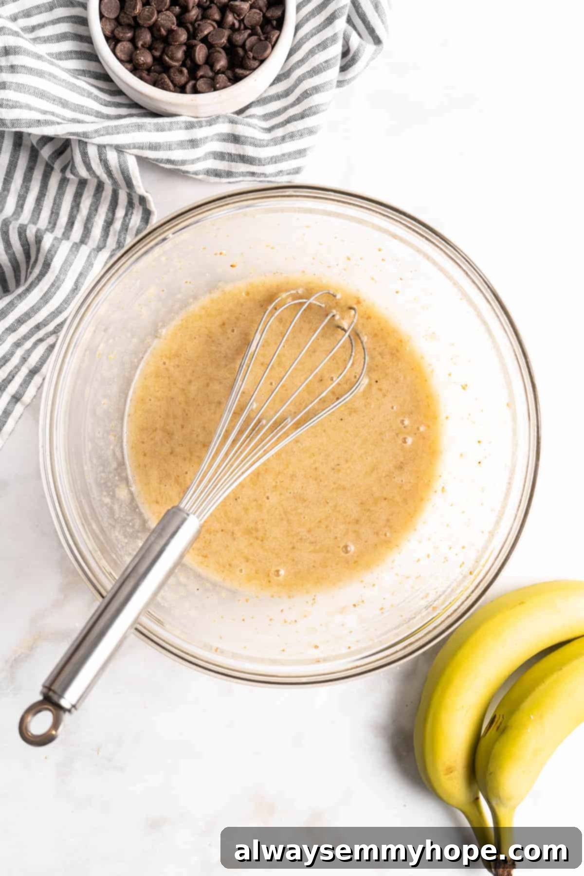 These easy chocolate banana muffins are moist, soft, and bursting with chocolate. They're made without refined sugar, gluten-free, and vegan! Whisking wet ingredients for muffins in glass bowl