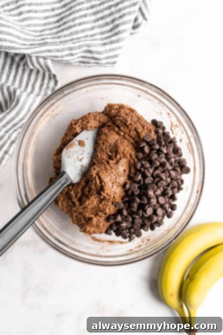These easy chocolate banana muffins are moist, soft, and bursting with chocolate. They're made without refined sugar, gluten-free, and vegan! Chocolate chips and muffin batter in glass bowl