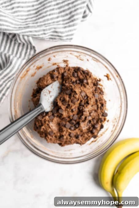 These easy chocolate banana muffins are moist, soft, and bursting with chocolate. They're made without refined sugar, gluten-free, and vegan! Chocolate muffin batter in glass bowl with spatula