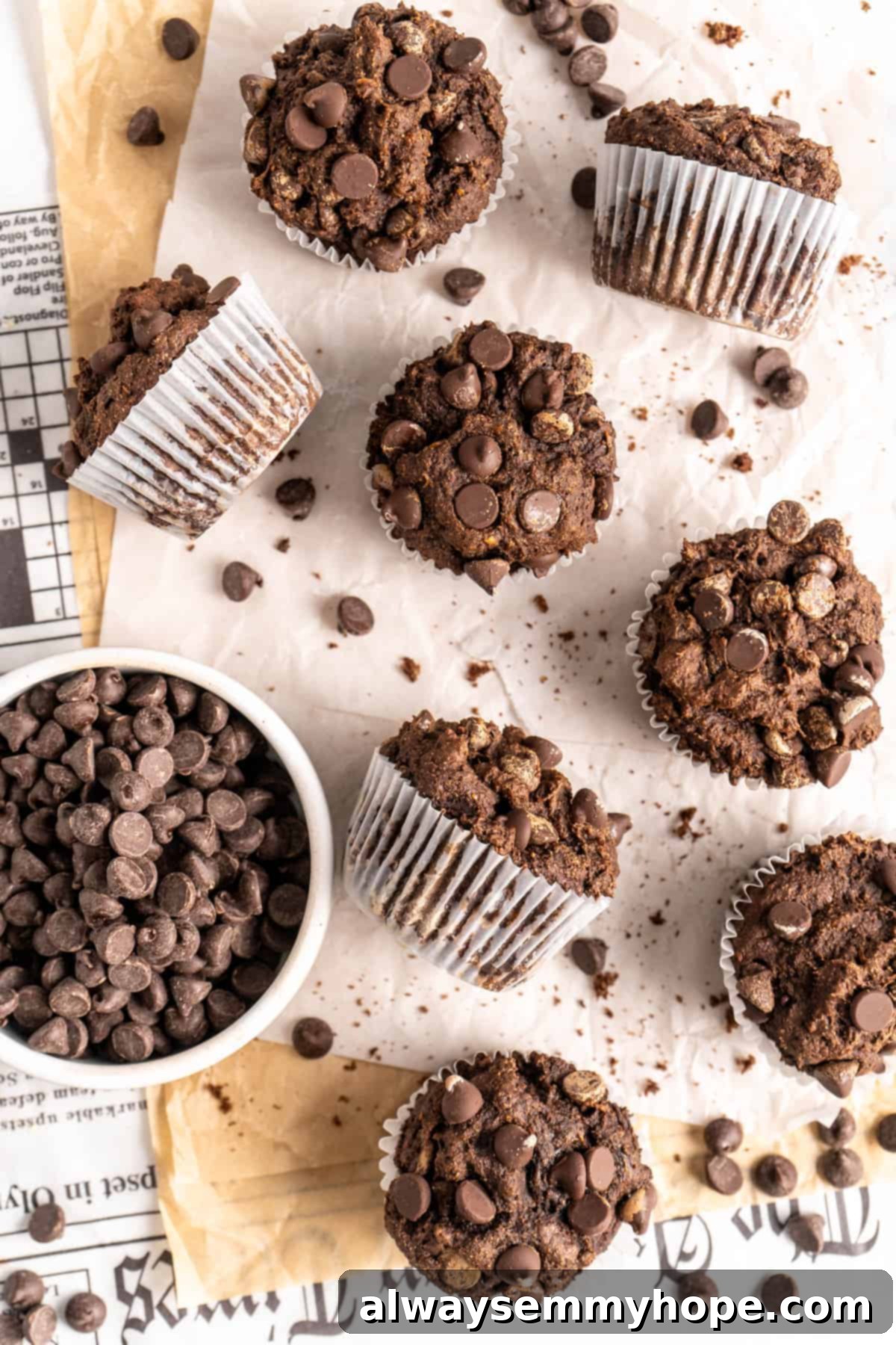 These easy chocolate banana muffins are moist, soft, and bursting with chocolate. They're made without refined sugar, gluten-free, and vegan! Overhead view of assorted double chocolate banana muffins on a countertop, surrounded by scattered chocolate chips.