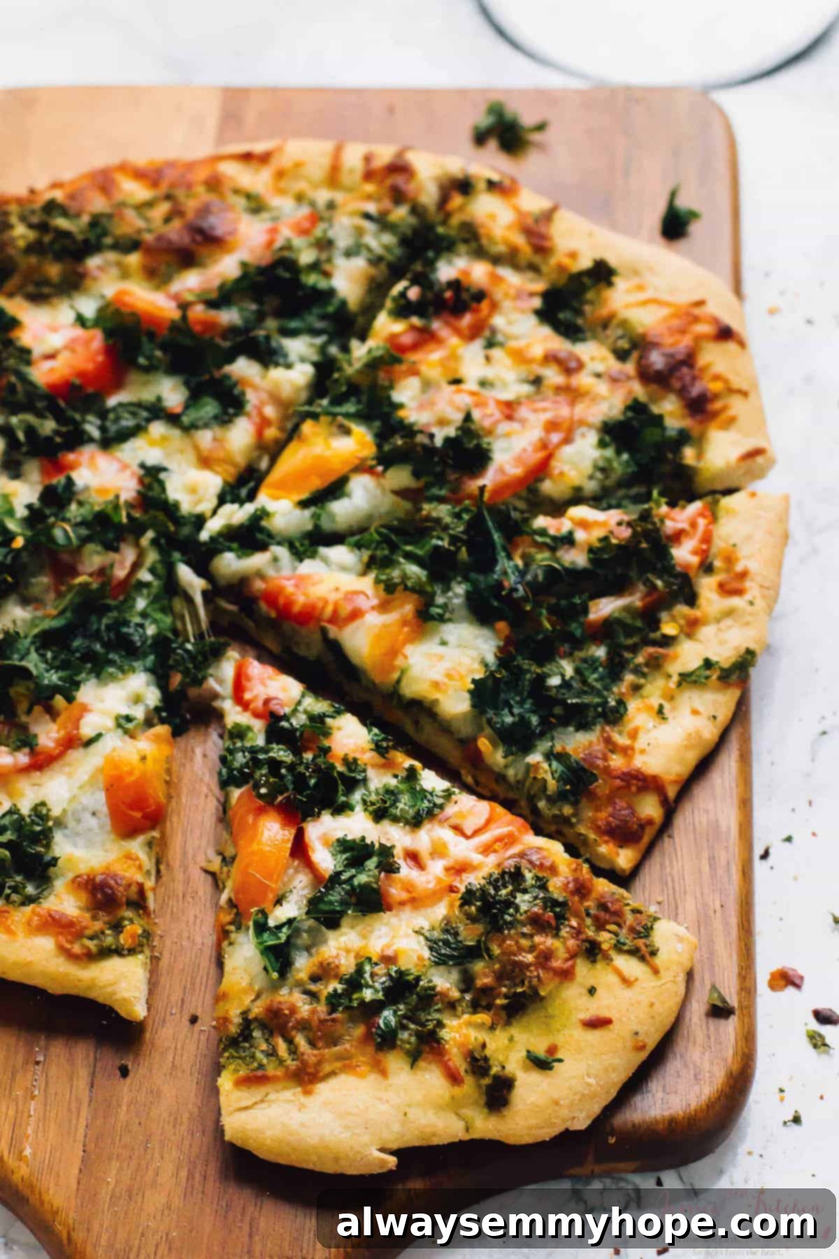 Kale pesto pizza on wooden cutting board
