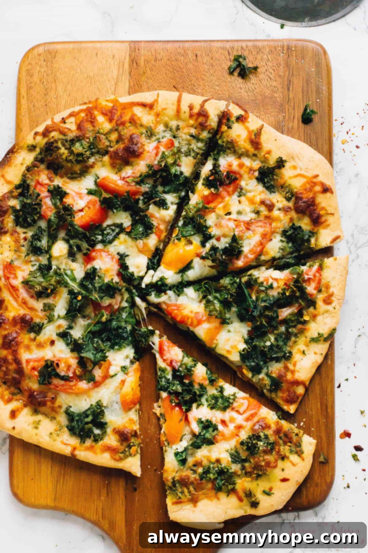 Overhead view of kale pizza on wood cutting board