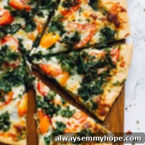 Top down shot of kale pesto pizza slices on a board.