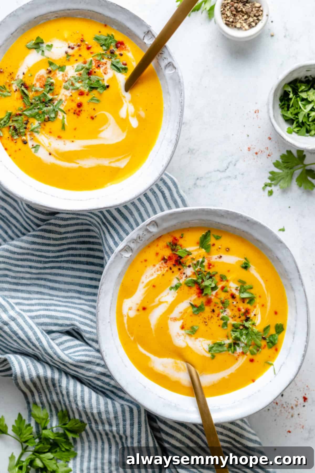 Golden Roasted Carrot Ginger Soup 2 Two bowls of roasted carrot soup on blue and white striped tea towel