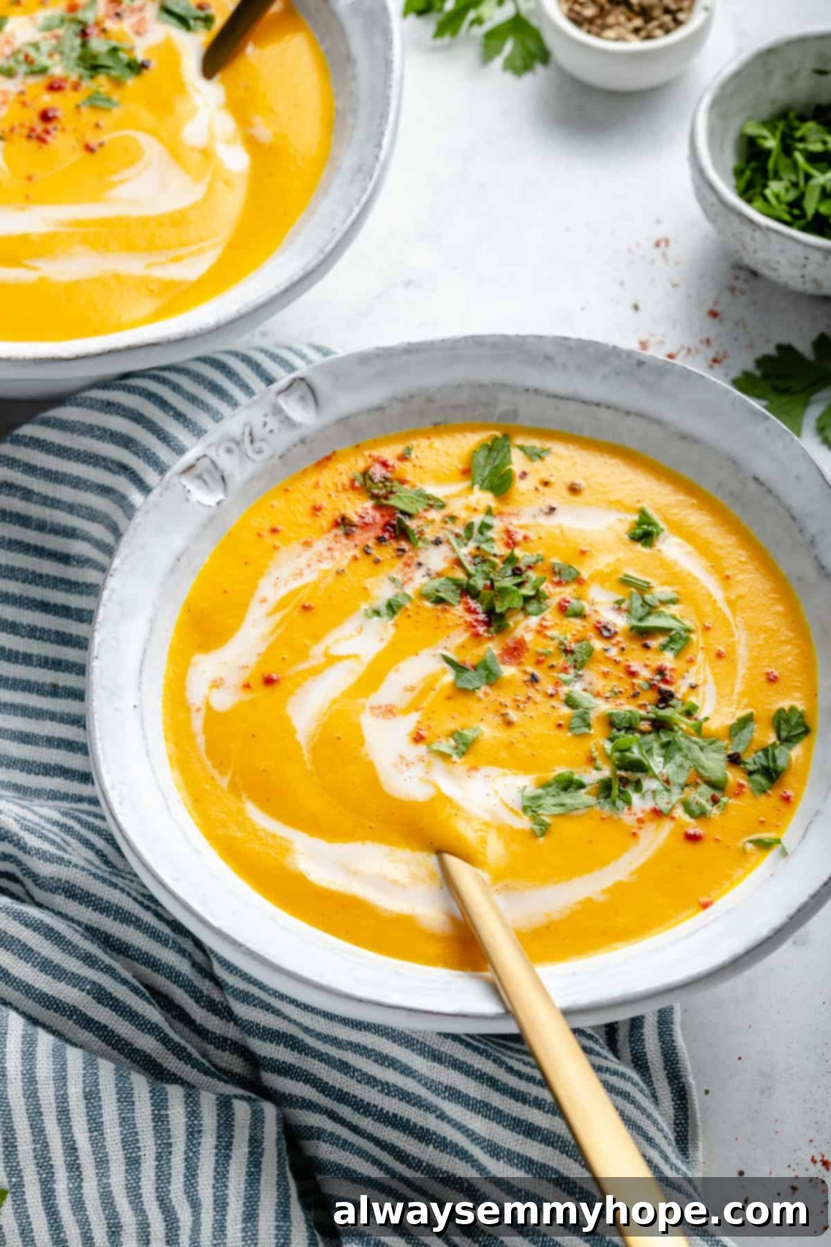 Golden Roasted Carrot Ginger Soup 11 Carrot soup in bowl with spoon set on striped tea towel