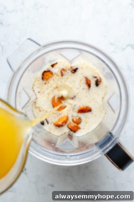 Golden Roasted Carrot Ginger Soup 7 Overhead view of broth being poured into blender with coconut milk and roasted carrots