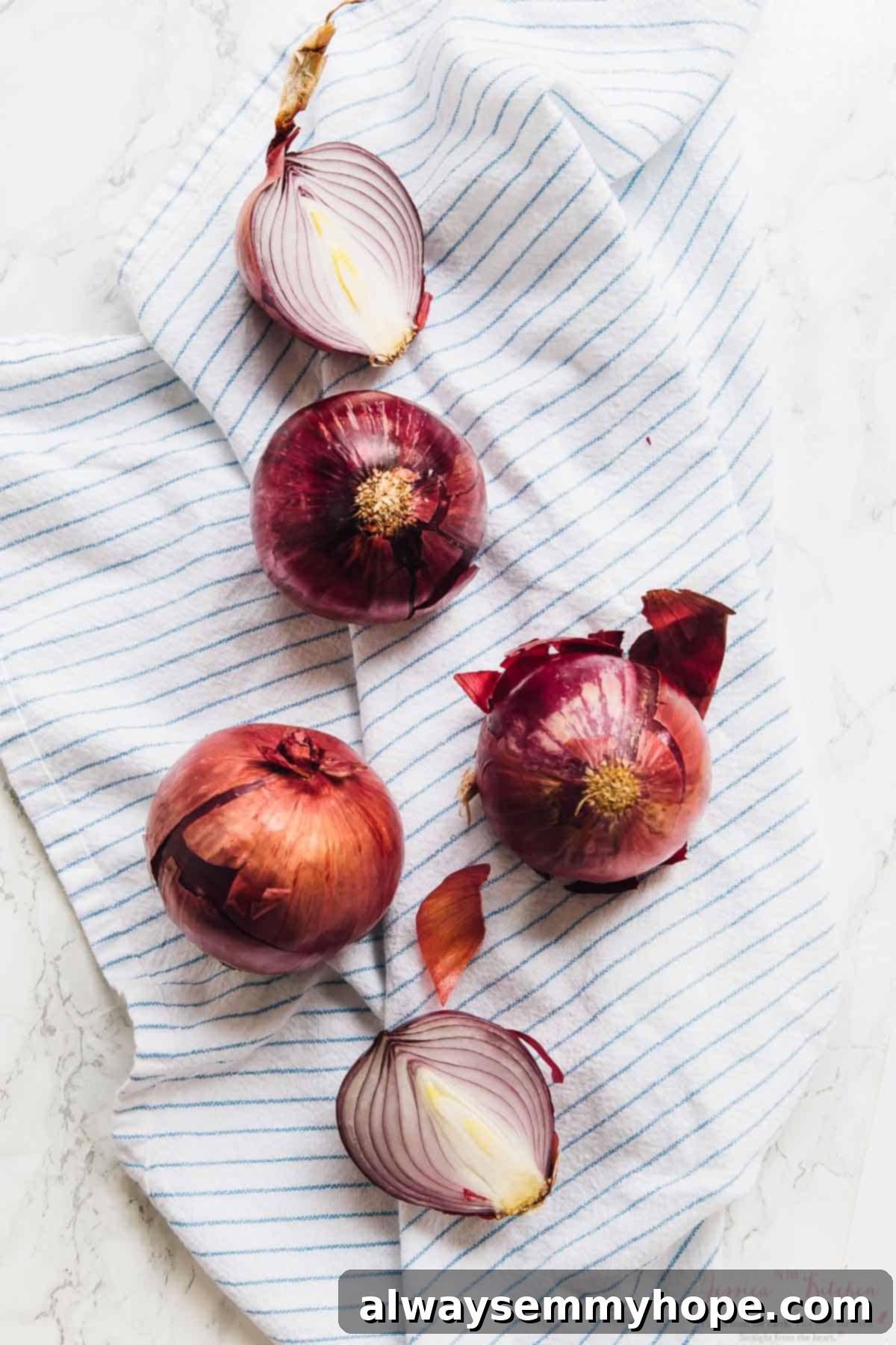 Overhead view of raw red onions on a clean tea towel, ready for slicing.