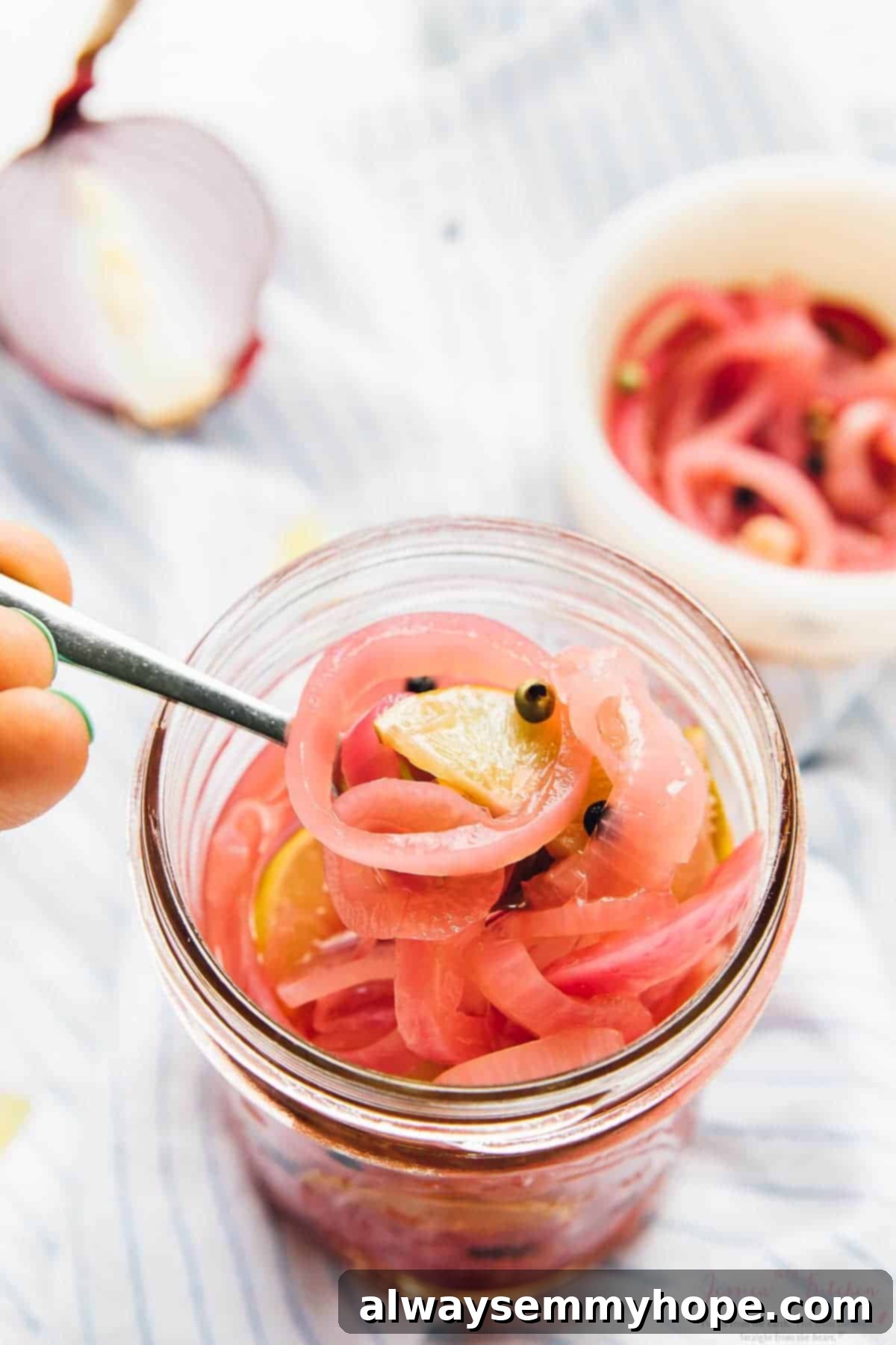 A spoon digging into a jar of quick pickled red onions, showing their texture.