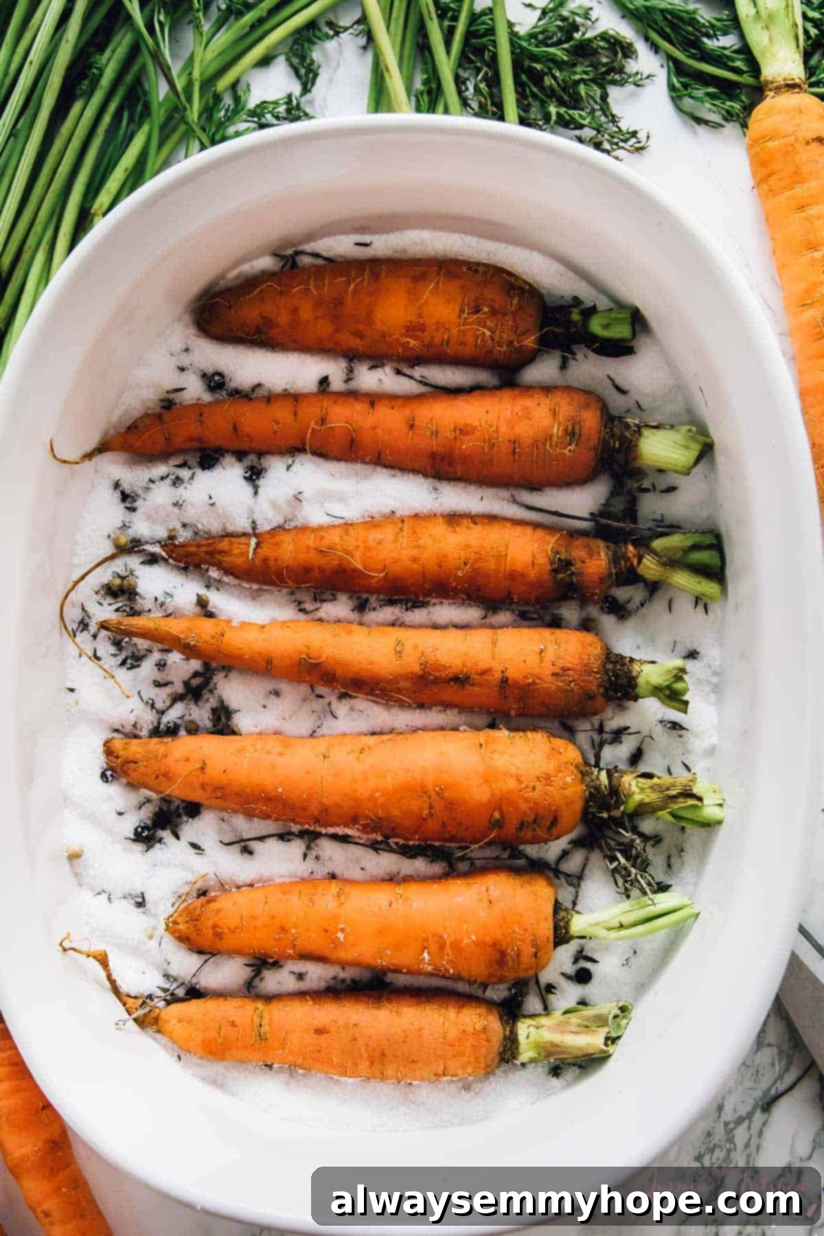 The Alchemy of Salt Roasted Carrots 4 Carrots nestled in a bed of coarse salt in a white baking dish, prepared for the oven.