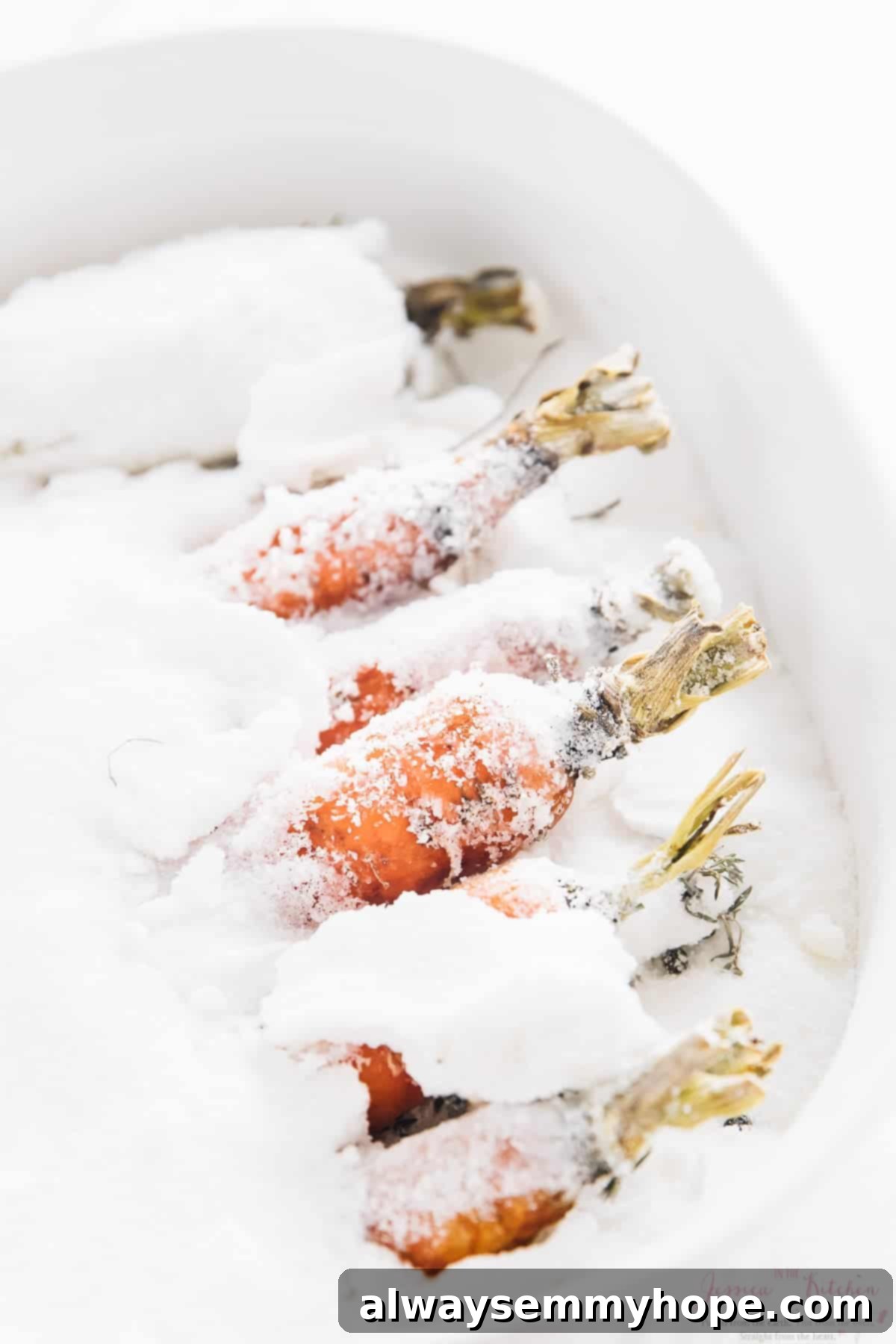 The Alchemy of Salt Roasted Carrots 6 A close-up view of carrots completely covered in a thick layer of coarse salt in a baking dish.