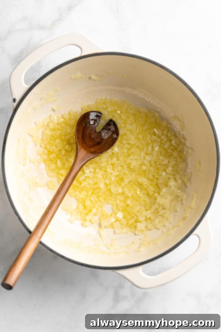 Sautéing Onions for Butternut Squash Soup Overhead view of diced onions cooking in a large pot with a wooden spoon