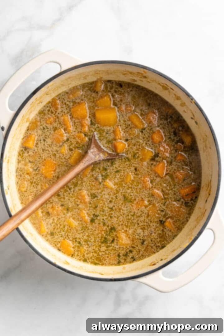 Cooked Butternut Squash Soup in Pot Overhead view of butternut squash soup in pot with a wooden spoon, ready for blending