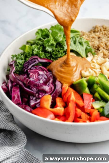 Generously drizzle the delicious peanut ginger dressing over your prepped Thai quinoa salad ingredients before tossing. A hand pouring the smooth peanut ginger dressing over a large bowl of colorful Thai quinoa salad ingredients, ready for tossing.
