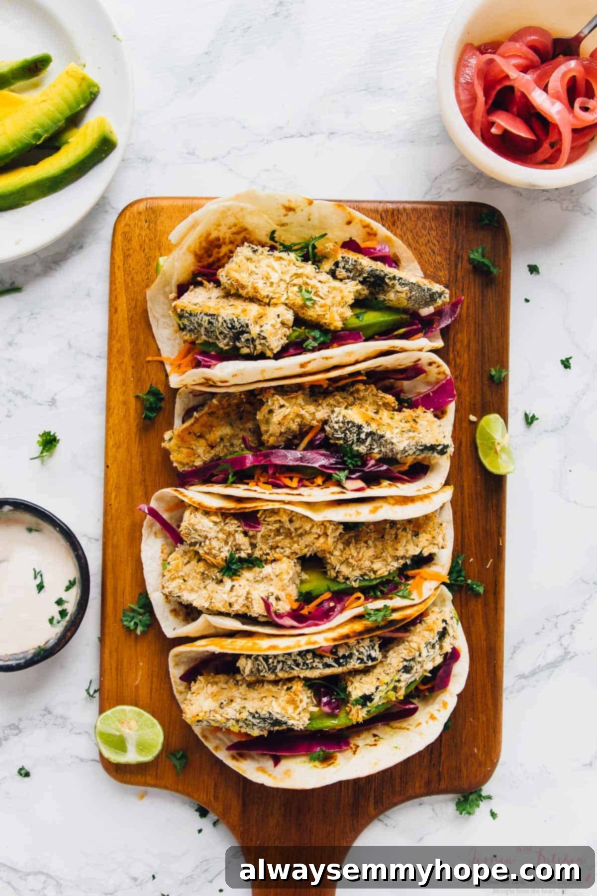 Overhead view of four crispy zucchini tacos beautifully arranged on a wooden board, with fresh cilantro, lime, and jalapeños in the background.