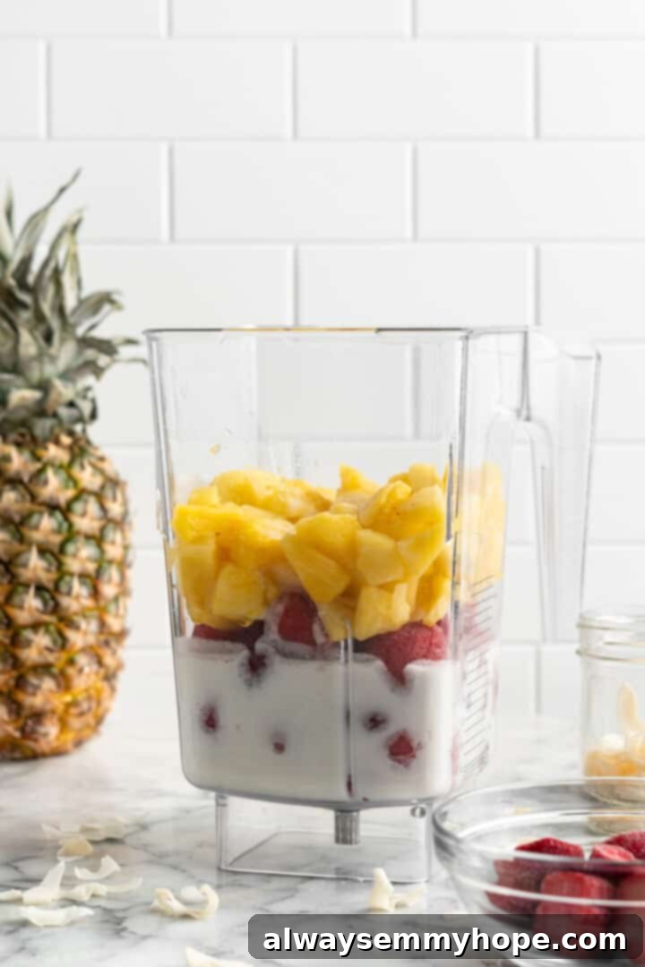 This vegan strawberry pineapple smoothie is light, refreshing, and ready to drink in just 5 minutes. You only need 3 ingredients to make it! Blender jar filled with frozen strawberries, cubed pineapple, and coconut milk, perfectly portioned and ready to be blended into a delicious smoothie.