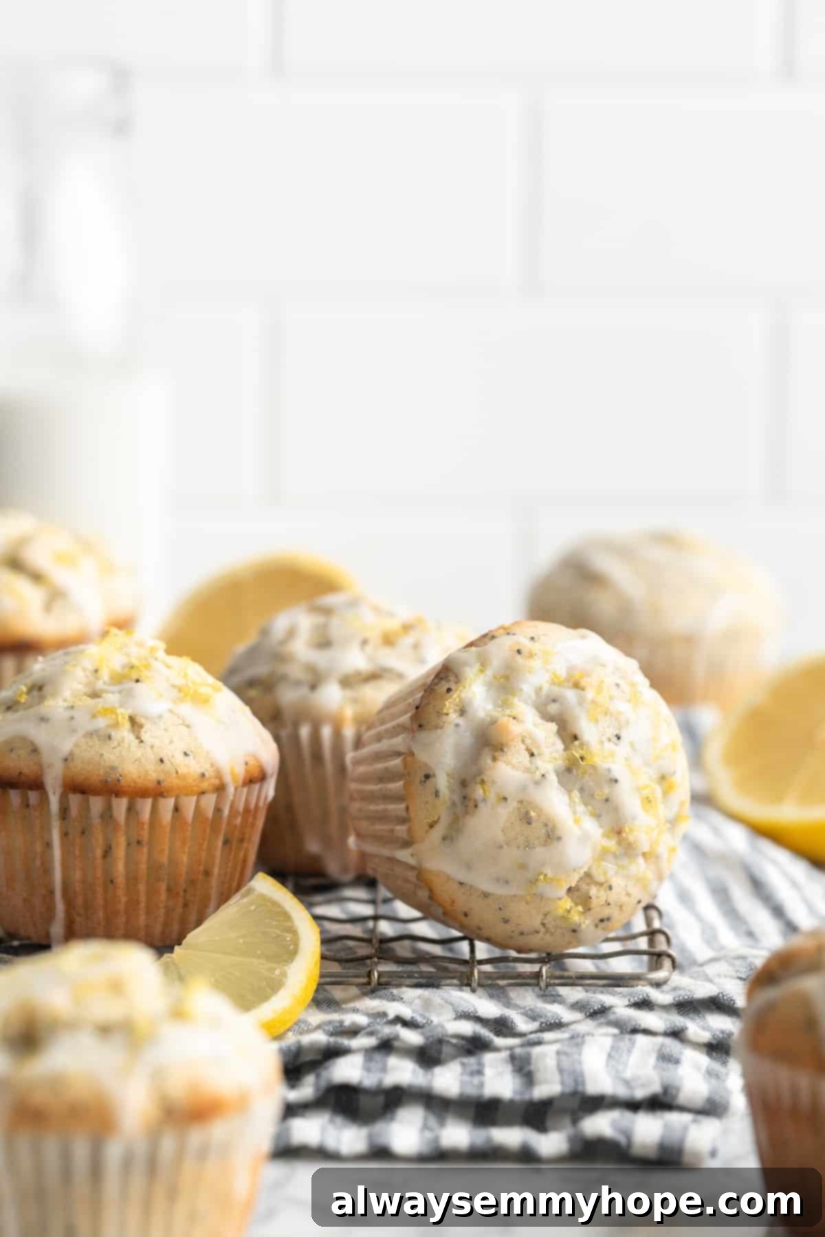 Three vegan lemon poppyseed muffins cooling on a wire rack, one on its side to maintain its dome, showcasing their golden-brown color