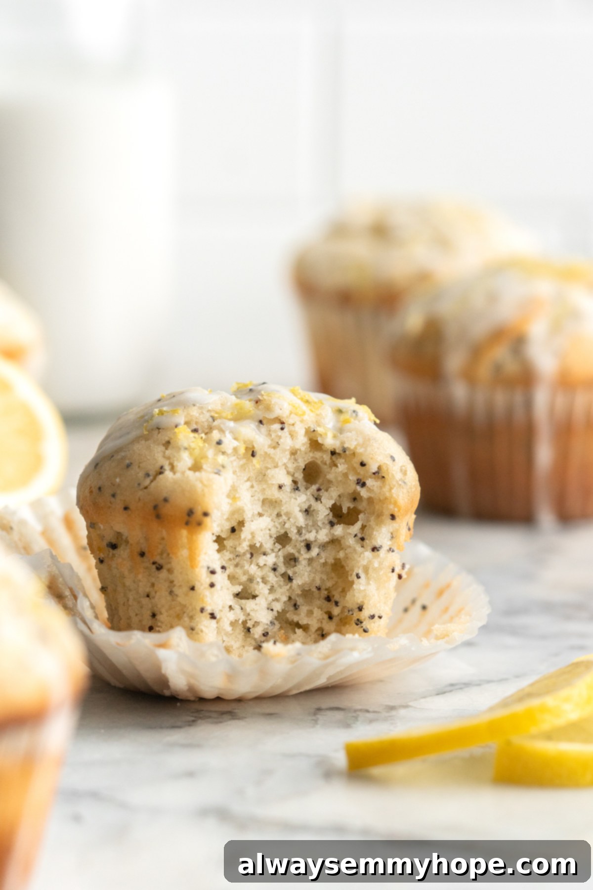 Close-up of a vegan lemon poppyseed muffin with a bite taken out, revealing its moist, fluffy interior and poppyseed distribution