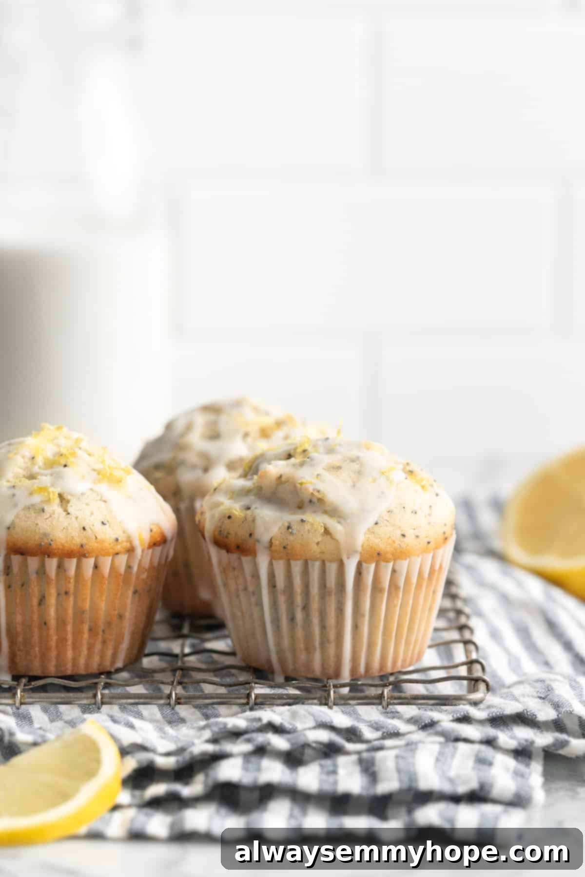 Three golden brown vegan lemon poppyseed muffins cooling on a wire rack, with one muffin tilted on its side to preserve its dome