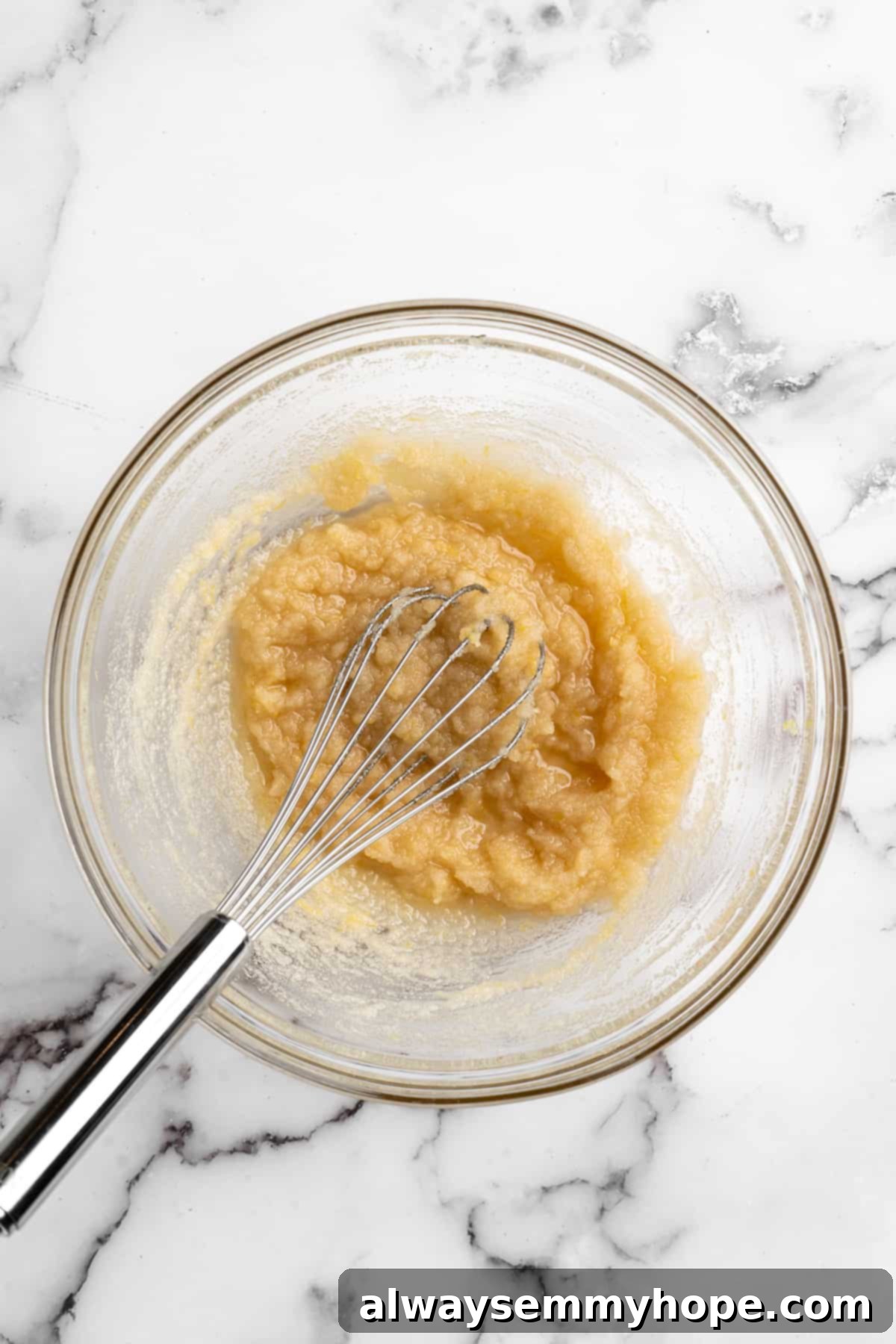 Overhead view of wet ingredients (sugar, oil, extracts, zest) for vegan muffins in a glass mixing bowl before whisking
