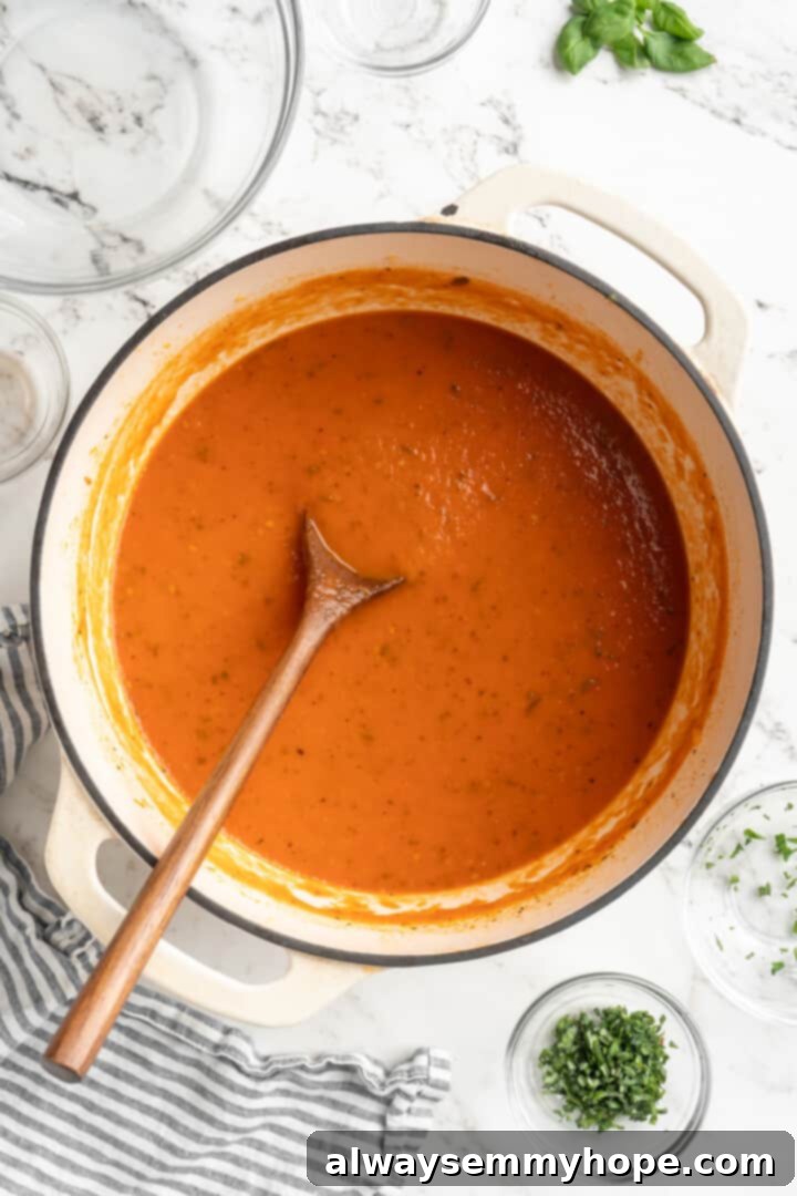 The homemade tomato sauce has simmered to perfection, awaiting the fresh basil before blending. Pot of homemade tomato sauce after simmering, before adding fresh basil