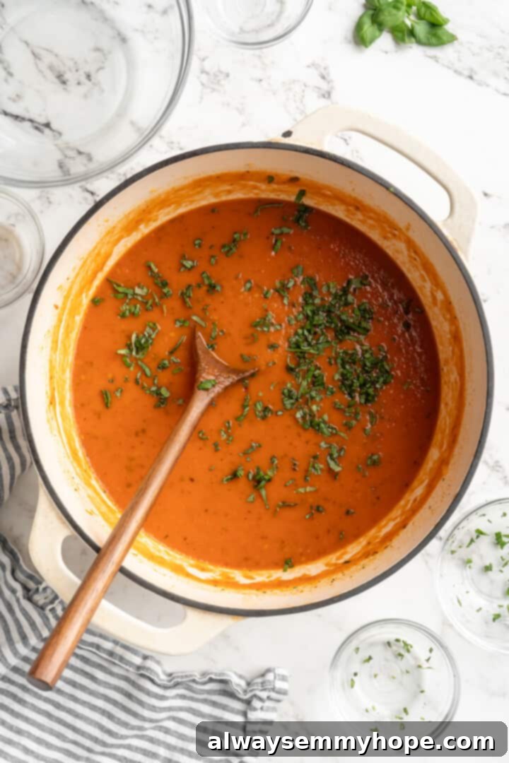 Freshly chopped basil is stirred into the warm homemade tomato sauce, adding a fragrant and essential finishing touch. Stirring fresh basil into a pot of finished homemade tomato sauce