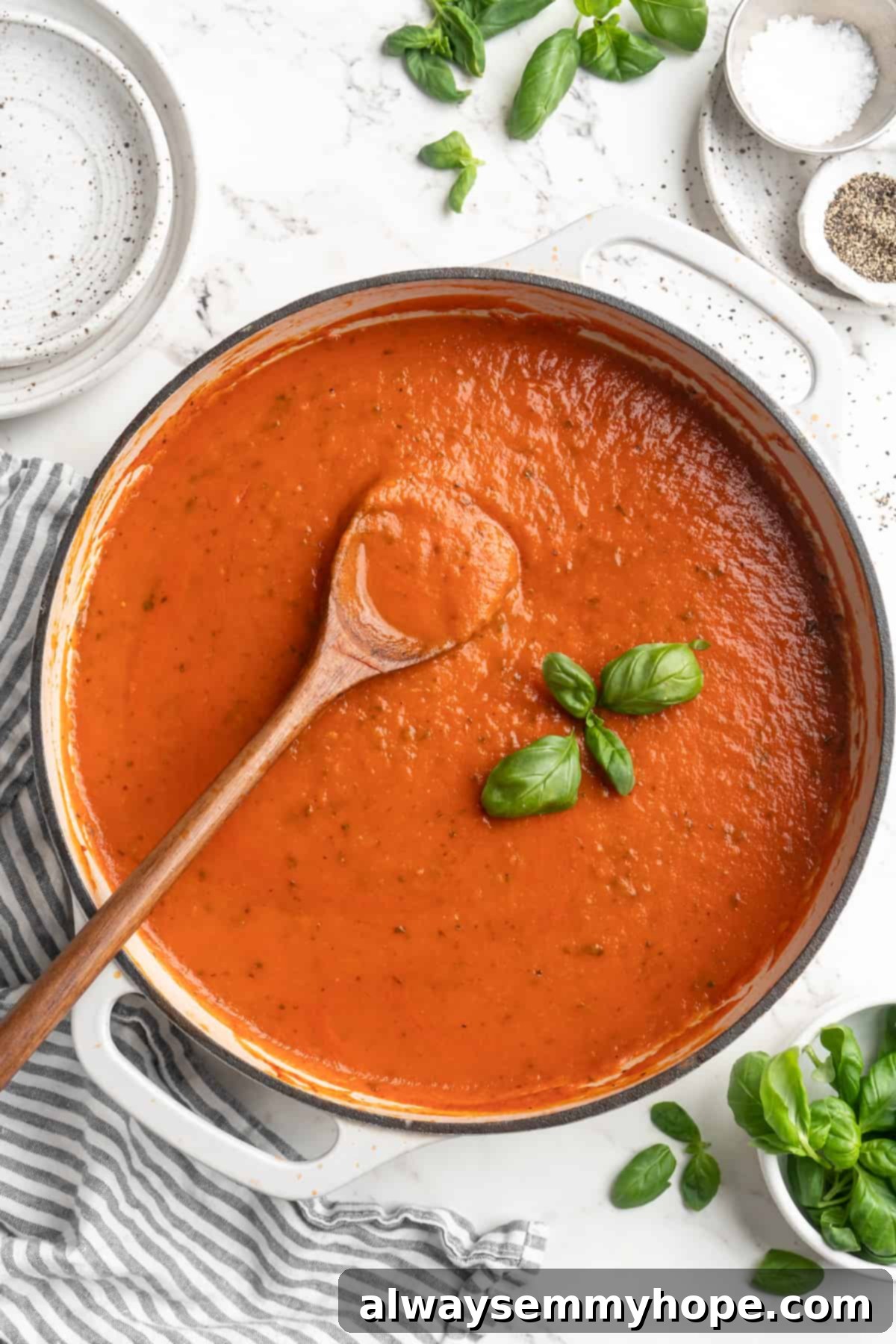 A top-down view of the beautifully finished homemade tomato sauce, rich and smooth, garnished with a fresh basil sprig and wooden spoon. Overhead view of rich homemade tomato sauce in a pot, garnished with a basil sprig and wooden spoon