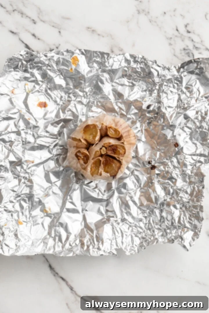 Close-up of a head of perfectly roasted garlic, showing its golden-brown, soft cloves. Essential for flavor in our homemade tomato sauce. Overhead view of a head of roasted garlic, golden brown and soft