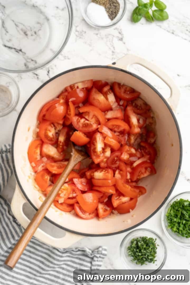 Chopped ripe tomatoes are added to the pot with the golden onions, beginning the journey to a rich homemade tomato sauce. Overhead view of chopped ripe tomatoes added to a pot with sautéed onions