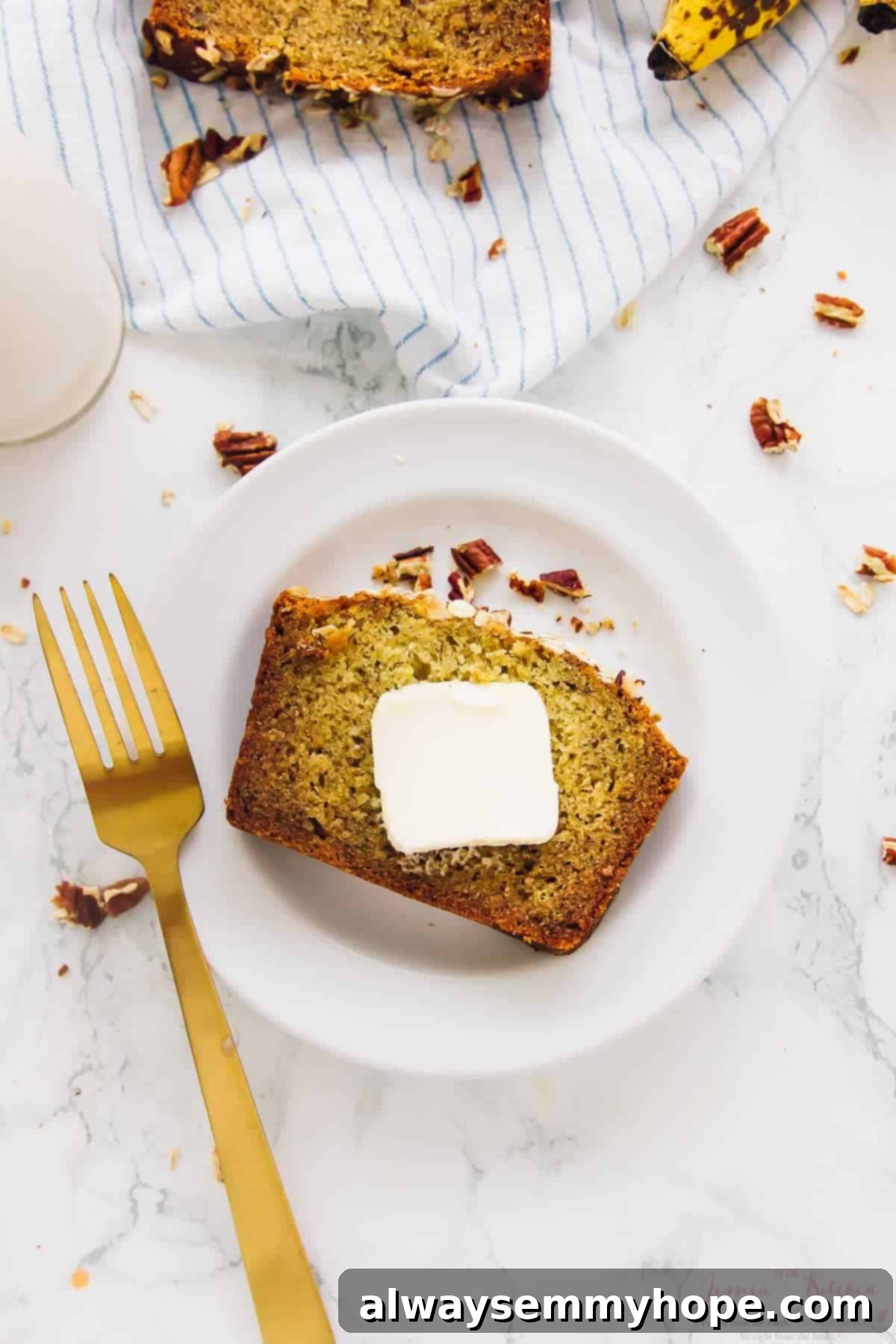 This is the best gluten-free vegan banana bread! Soft, moist, and easy to make with simple ingredients. Enjoy it with your favorite mix-ins! Overhead view of vegan gluten-free banana bread slice on plate with pat of butter