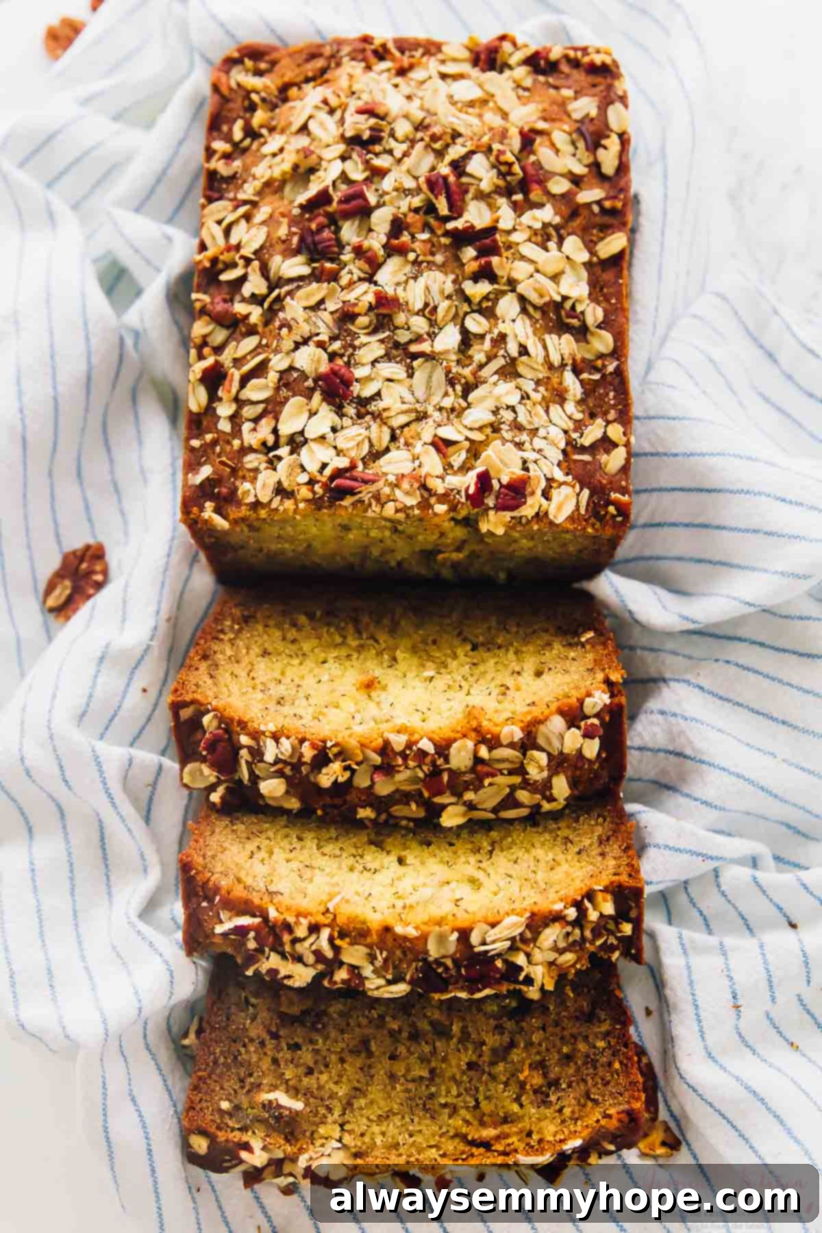 This is the best gluten-free vegan banana bread! Soft, moist, and easy to make with simple ingredients. Enjoy it with your favorite mix-ins! Overhead shot of vegan banana bread cut into slices on a striped cloth.
