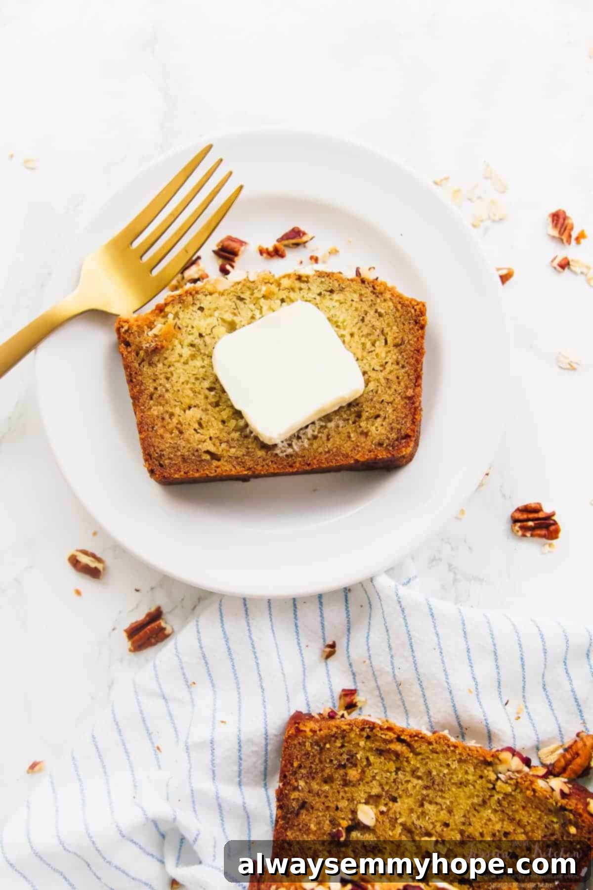 This is the best gluten-free vegan banana bread! Soft, moist, and easy to make with simple ingredients. Enjoy it with your favorite mix-ins! Overhead view of gluten-free vegan banana bread slice on plate with pat of butter