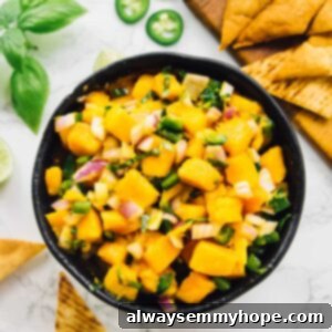 Overhead shot of mango salsa in a bowl with pita chips in background
