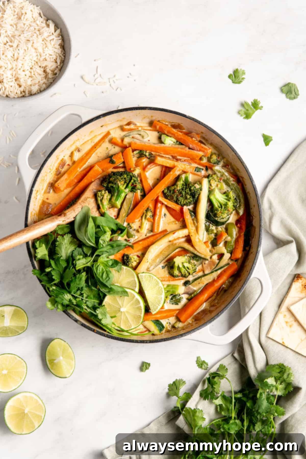 Effortless Thai Green Curry 13 A wooden spatula stirring cooked vegetables in a pan filled with a creamy, rich curry sauce.