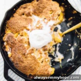 Half eaten breakfast peach cobbler in cast iron skillet with gold spoon