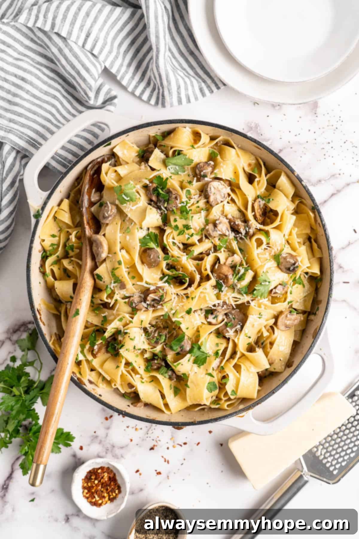 Overhead view of Garlic Mushroom Pasta in a pan with a wooden spoon, ready to be served.