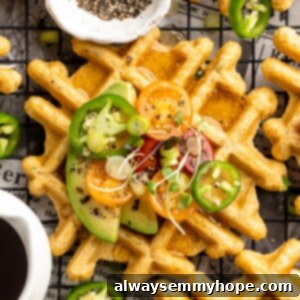 Overhead view of jalapeno cornbread waffle on wire rack, topped with avocado, tomato, and microgreens
