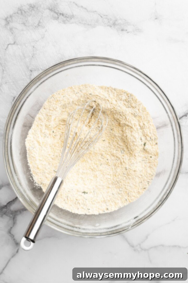 Dry ingredients for cornbread waffles in bowl with whisk