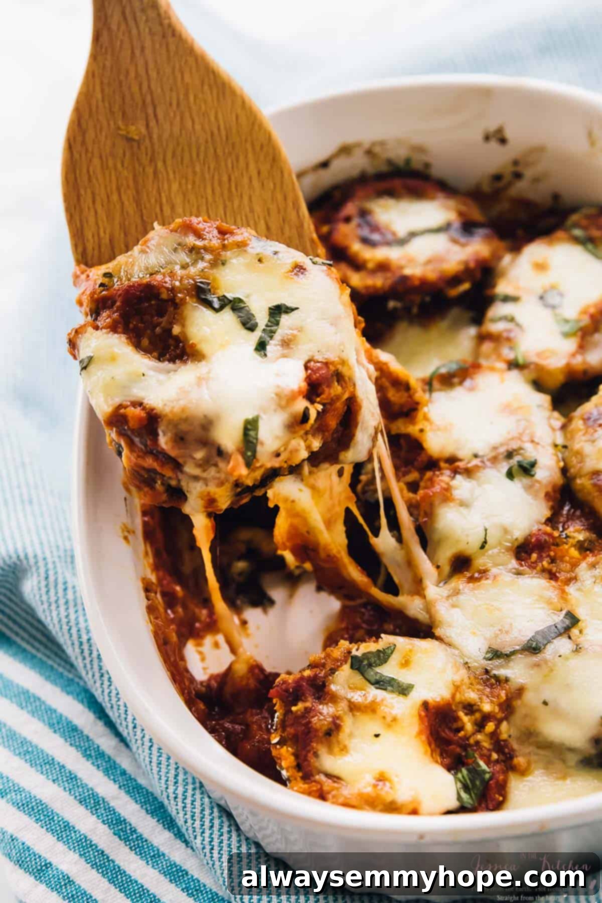 A spatula scooping a generous portion of Baked Eggplant Parmesan from a casserole dish, highlighting the layers.
