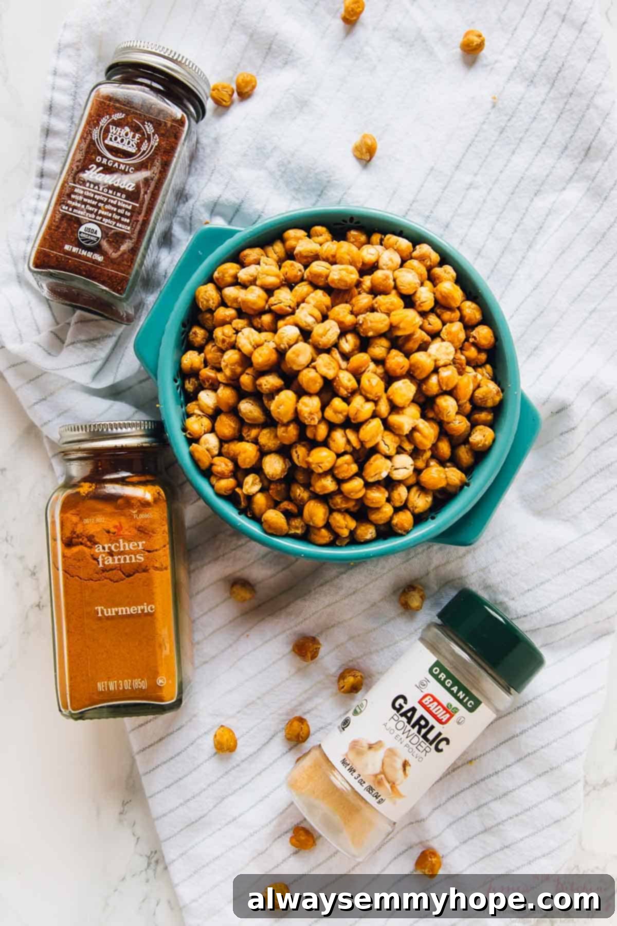 Overhead shot of crispy roasted chickpeas in a rustic bowl, surrounded by various spice jars.